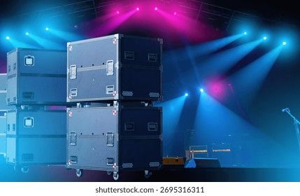 Gestapelte Flightcases auf einer Konzertbühne unter blauem und pinkem Licht.