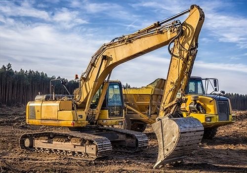 Gelber Bagger und Muldenkipper auf einer Baustelle im Wald